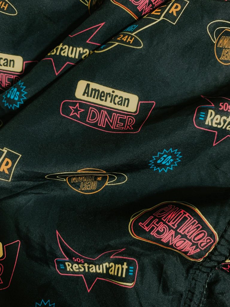 Details of trendy cotton shirt with colorful retro styled inscriptions and logos of American diners