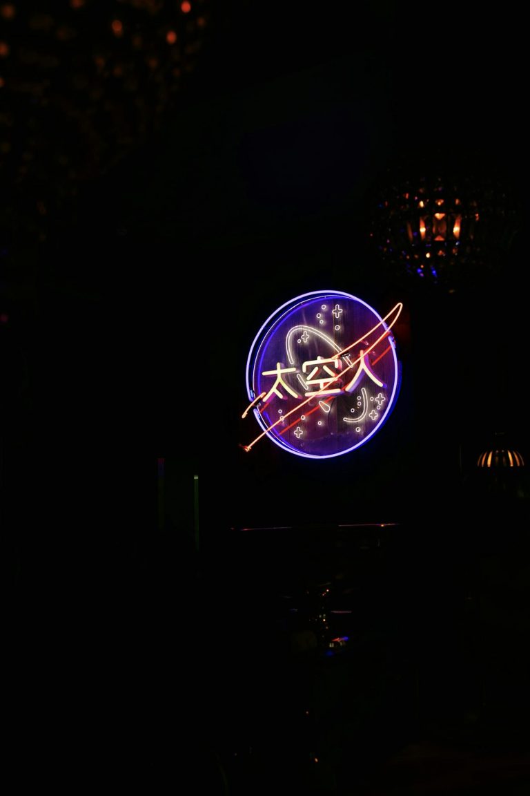 Vibrant neon sign depicting space theme on a black background.